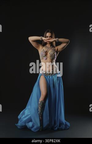 Una donna esegue una danza con un serpente in una zona buia. Si muove con grazia mentre tiene il serpente. L'ambientazione evidenzia i suoi movimenti e aggiunge focu Foto Stock