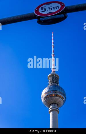 Vista dall'angolo basso dell'iconica torre della televisione di Berlino incorniciata da un cartello stradale con restrizioni di altezza contro un cielo azzurro. Fernsehturm, verticale, Copia spazio. Foto Stock