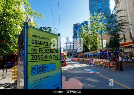 Vancouver, Canada - 12 giugno 2026: Un panino verde luminoso che dà il benvenuto ai visitatori nella zona pedonale di Granville all'isolato 900, con l'auto-fr Foto Stock