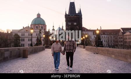 Mentre il crepuscolo scende su Praga, le coppie si godono una romantica passeggiata mano nella mano attraverso l'iconico Ponte Carlo. Foto Stock