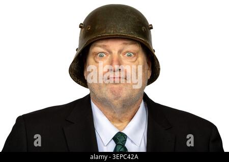 Unshaven uomo in tuta e cravatta con casco militare in stile seconda Guerra Mondiale isolato su sfondo bianco Foto Stock