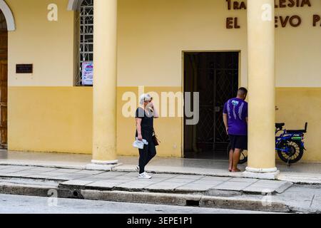 Scena di strada fuori da una chiesa storica a Ciego de Ávila, Cuba, con residenti locali sul marciapiede Foto Stock