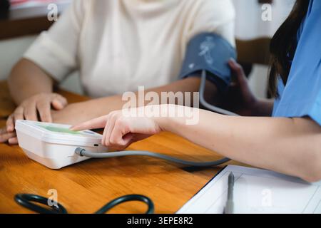 Primo piano del misuratore della pressione sanguigna. L'infermiere indica i dati nel dispositivo di lettura della pressione sanguigna del monitor e tiene il bracciale sul braccio. Le mani lavorano calme Foto Stock