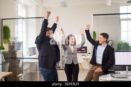 Felice team aziendale che si esibisce in ufficio, i colleghi festeggiano i risultati insieme Foto Stock