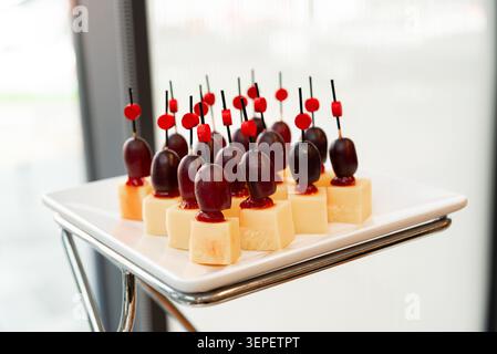 Vista ravvicinata di antipasti al formaggio e all'uva serviti su un piatto bianco per un elegante catering per feste. Foto Stock