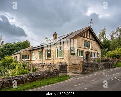 Ampia prospettiva orizzontale del paesaggio che mostra l'esterno del Museo Eyam accanto all'asfalto curvo di Hawkhill Road nel villaggio storico di Ey Foto Stock