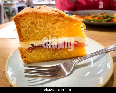 Una fetta di torta Victoria Sponge, due strati di spugna per torte intorno a uno strato di glassa di burro e marmellata Foto Stock