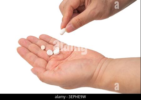Primo piano di una persona che prende una pillola medica da una mano piena di varie compresse, concetto di assistenza sanitaria. Foto Stock