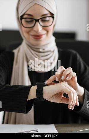 Donna in Hijab che usa lo Smartwatch Foto Stock