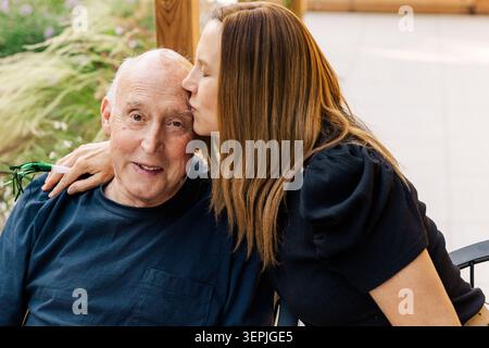 Figlia che bacia un padre anziano all'aperto Foto Stock