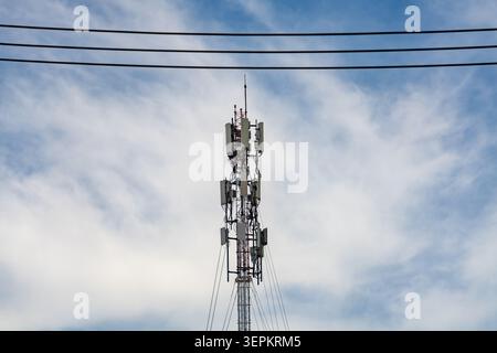 Questa immagine presenta una torre di comunicazione alta con più antenne contro un cielo nuvoloso, che simboleggia connettività, comunicazione e tecnologia moderna Foto Stock