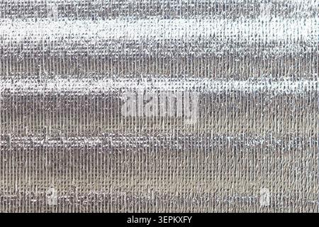 Primo piano dettagliato di una superficie in lamina di alluminio increspata che mostra una texture metallica lucida e riflettente, che enfatizza le rughe e il fascino increspato Foto Stock