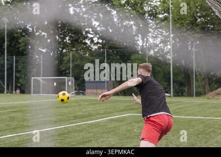 Un portiere maschile si allena su un campo da calcio mentre pratica la difesa. Questa sessione si concentra sullo sviluppo delle competenze. Foto Stock