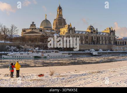 Skyline storico di Dresda, Germania, in inverno con l'Accademia delle Belle Arti, la terrazza di Brühl e un piroscafo a pale sul ghiacciato fiume Elba Foto Stock