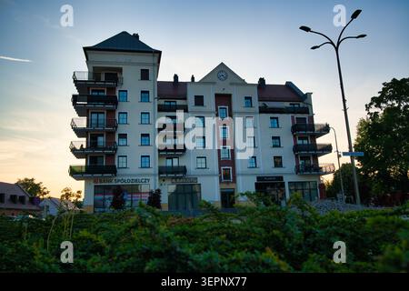 Edificio di appartamenti residenziali con filiale di banca e balconi al tramonto - città di Lubin. Foto Stock