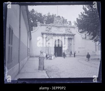 Una fotografia stampa cattura l'ingresso dell'Arsenale di Tolone a Var, Provenza-Alpi-Côte d'Azur, Francia, il 9 maggio 1905, presentando una porta formale con dettagli architettonici tra cui frontone, struttura della porta e area di accesso pavimentata. Foto Stock