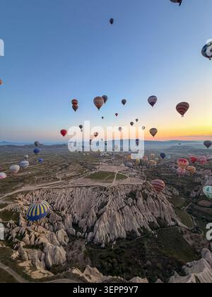 Questa splendida vista aerea mostra colorate mongolfiere che si innalzano sopra le formazioni rocciose uniche della Cappadocia durante l'alba. Foto Stock