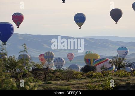 Una vivace scena di mongolfiere che si innalzano sopra l'unico paesaggio della Cappadocia, mostrando la sua bellezza naturale. Foto Stock