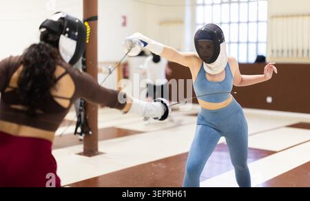 Un gruppo di recinti si allena in duelli e fa uscire i colpi sui cuscini in palestra Foto Stock
