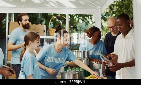 Nell'ambito della campagna alimentare senza scopo di lucro, si vede da un lato che le donne che forniscono cibo gratuito ai volontari meno fortunati e amichevoli che forniscono aiuti umanitari ai poveri e ai senzatetto. Foto Stock