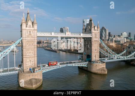 Veduta aerea del Tower Bridge sul Tamigi con un autobus rosso a due piani che attraversa e lo skyline della City of London dietro, London, England, United Foto Stock