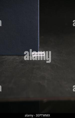 Etichetta Word per seminari sotto Upright Book su sfondi texture scuri Foto Stock