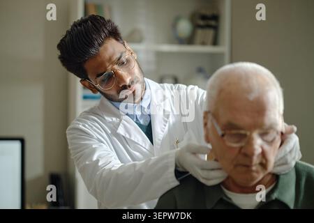 Uomo anziano che riceve l'esame del collo dal dottore in clinica Foto Stock