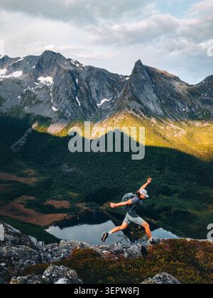Uomo atleta trail running da solo sulla scogliera di montagna sopra il lago in Norvegia viaggio avventura escursionismo all'aperto viaggiatore attivo godendo di uno stile di vita sano Foto Stock