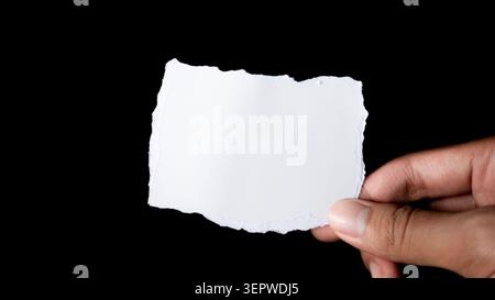 Carta bianca strappata a mano su sfondo scuro Foto Stock