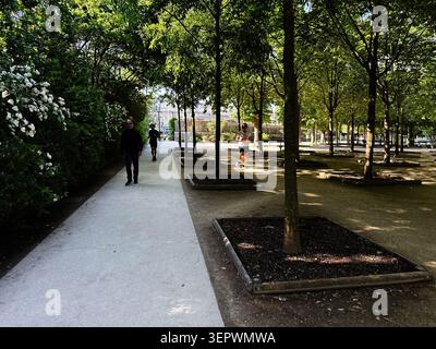 Parigi, Francia - 14 maggio 2026: Persone che camminano e fanno jogging lungo sentieri alberati ombreggiati in un tranquillo parco urbano di Parigi. Foto Stock