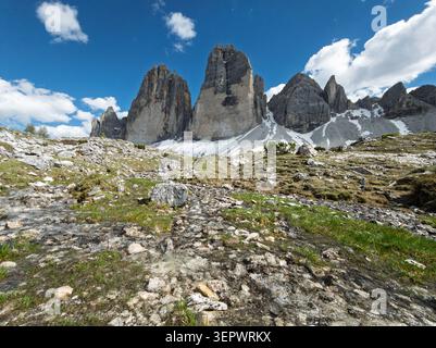 Le tre Cime di Lavaredo, cime delle Dolomiti italiane con prato roccioso e piccolo torrente alpino sotto il cielo azzurro, paesaggio alpino panoramico di Drei Zinn Foto Stock