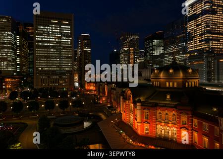 Edificio storico della stazione di Tokyo circondato da moderni grattacieli di notte a Yaesu Tokyo in Giappone, contrasto tra il quartiere storico e il quartiere degli affari Foto Stock