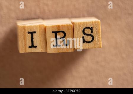 Testo IRS su blocchi di legno su sfondo marrone. Primo piano di lettere IRS su cubi di legno isolati su sfondo marrone semplice con spazio di copia Foto Stock