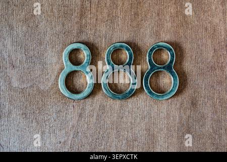Tre forme metalliche a numero otto disposte su una superficie di legno che simboleggiano l'infinito, l'equilibrio, la fortuna e il concetto numerico astratto Foto Stock
