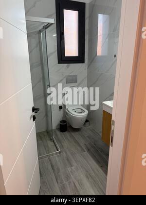 Interni del bagno dal design moderno con WC, finestra e doccia in marmo. Foto mobile Foto Stock