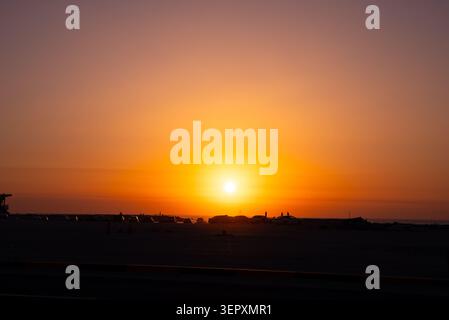 Tramonto spettacolare con un bagliore dorato sul campo nebbioso e sagome scure di alberi. Foto Stock