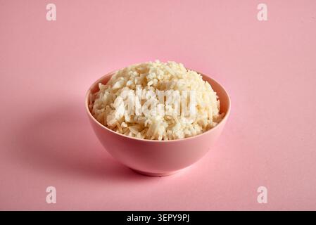 Ciotola di gustoso riso bianco bollito su sfondo rosa Foto Stock