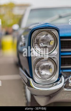 Complessivo doppio faro per auto d'epoca con cornice cromata lucida e lenti trasparenti che mettono in risalto lo stato di purezza rispetto alla finitura in vernice a due tonalità Foto Stock
