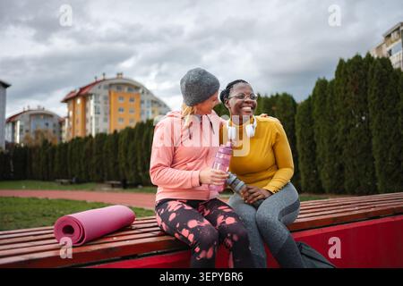 Felici e diverse donne amiche che si divertono insieme dopo l'esercizio fisico in un parco Foto Stock