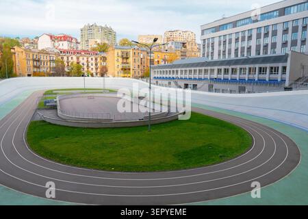 Moderno complesso sportivo all'aperto con pista ciclabile in cemento, piste da corsa e prato verde sullo sfondo di edifici urbani Foto Stock