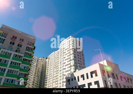Vista ad angolo basso dei moderni e alti edifici di appartamenti e della facciata del complesso residenziale contro il cielo azzurro limpido in una giornata di sole con luce rosa Foto Stock