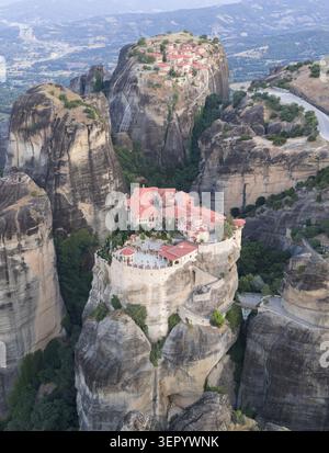 Vista aerea degli storici monasteri di Meteora arroccati su enormi colonne di pietra arenaria circondati da una lussureggiante vegetazione verde e da tortuose montagne Foto Stock