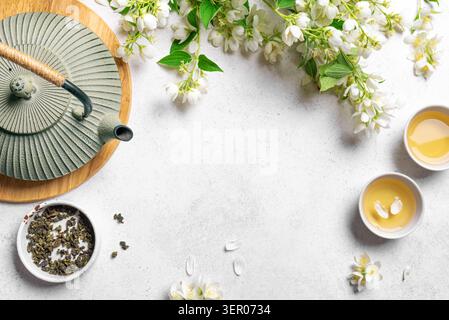 Tè verde giapponese con gelsomino in teiera in ghisa e tazze da tè su sfondo bianco, vista dall'alto, spazio copia. Tè al gelsomino naturale e fiori, modello f Foto Stock