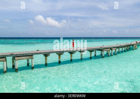 Il molo in legno delle Maldive si estende su fondali turchesi a mezzogiorno Foto Stock