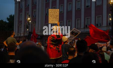 Tirana, Albania – 17 giugno 2026: I manifestanti tengono cartelli politici e bandiere albanesi fuori da un edificio governativo durante una protesta serale. Foto Stock