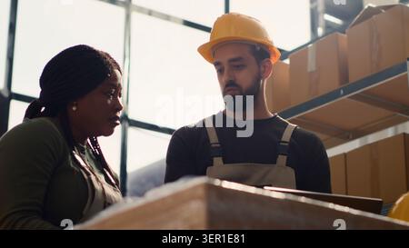 Responsabile del team di magazzino che si occupa della formazione introduttiva al nuovo tirocinante, insegnandogli le misure di sicurezza sulle corsie dell'area di stoccaggio, il responsabile svolge un tutorial di orientamento per tirocinante. Foto Stock