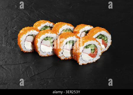 Panini di sushi con tobiko, cetrioli, salmone, surimi e formaggio spalmabile su una superficie di ardesia nera Foto Stock