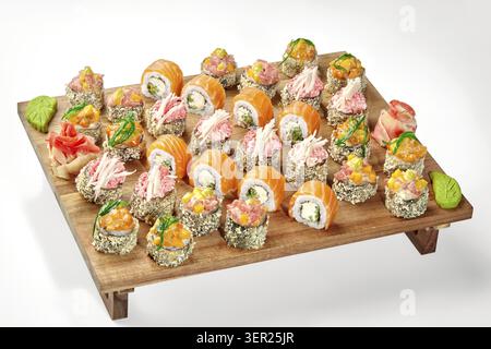 Varietà di sushi roll disposti su una tavola da servizio in legno, con ingredienti colorati e presentazione Foto Stock