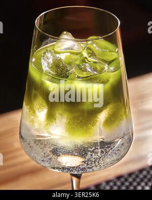 Rinfrescante cocktail matcha ghiacciato frizzante in un bicchiere sofisticato, che crea una bevanda vivace e invitante Foto Stock