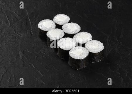 Panini di sushi con alghe nori, riso e crema di formaggio ripieno su una superficie di pietra nera, pronti per essere serviti Foto Stock